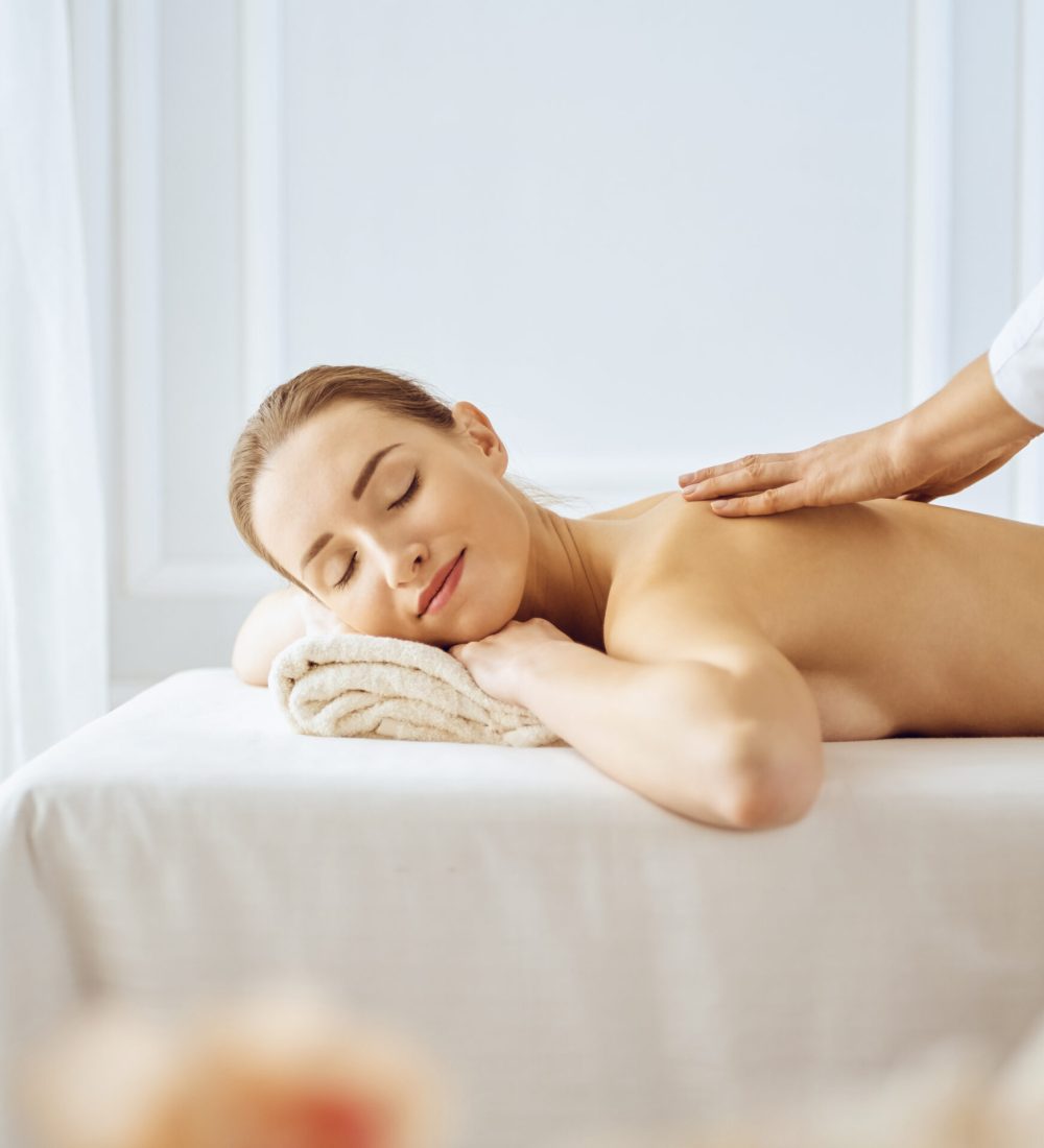 Beautiful woman enjoying back massage with closed eyes. Spa treatment concept.