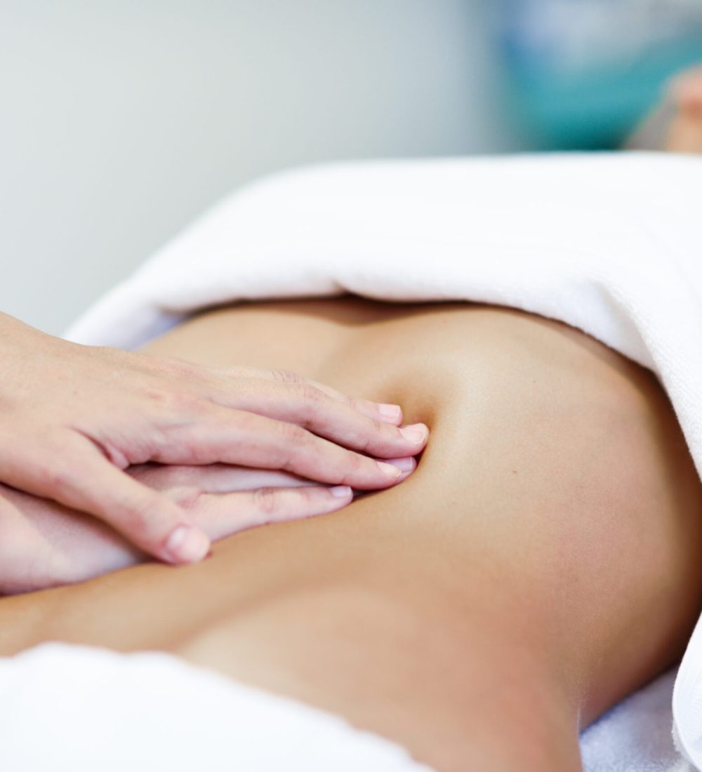 Hands massaging female abdomen.Therapist applying pressure on belly. Woman receiving massage at spa salon