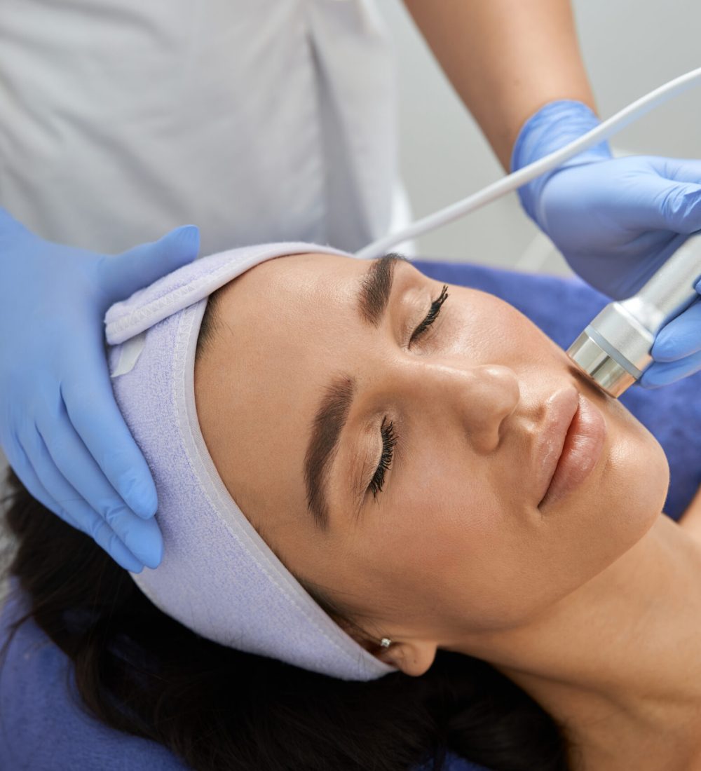 Professional cosmetologist is doing procedures for client in light cabinet