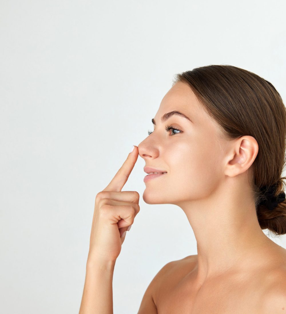 Side view of young attractive woman holding nose isolated on white background. Rhinoplasty surgery. Concept of beauty, plastic surgery, cosmetology, skin care, spa. Ad